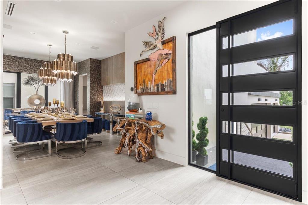 A modern entryway leads into a dining room with blue chairs and a root-wood console — 5131 W NEPTUNE WAY, TAMPA, FL