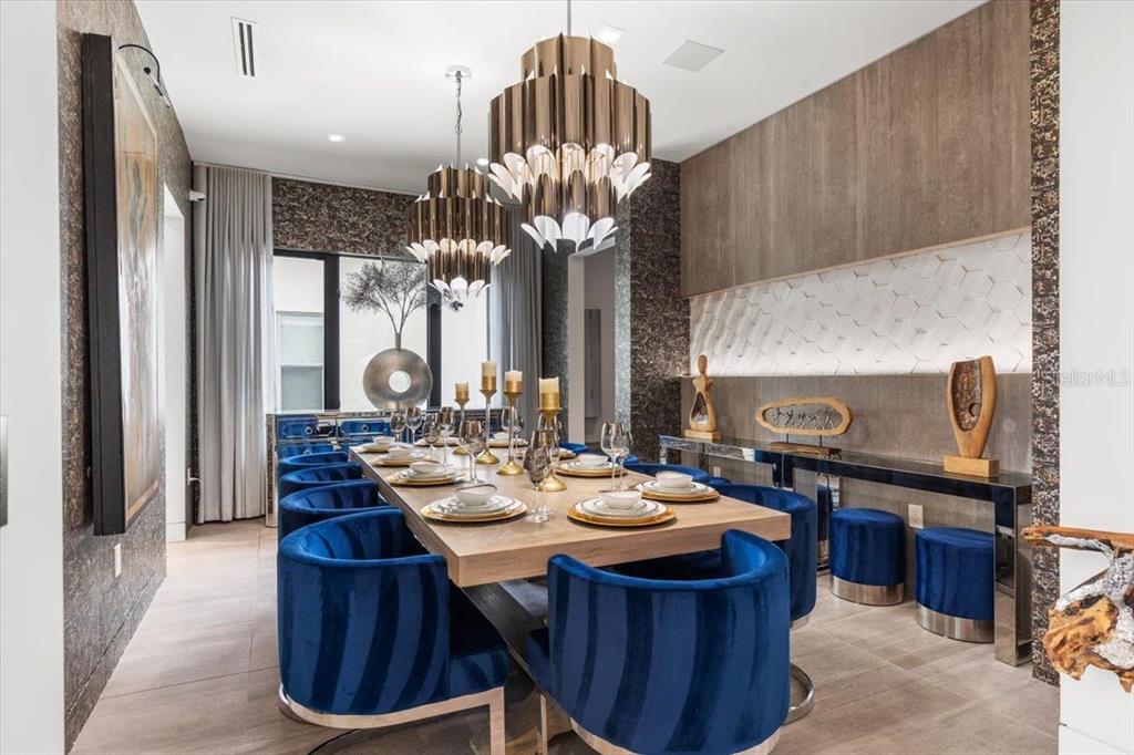 A dining room features a long wooden table, blue velvet chairs, and two tiered chandeliers — 5131 W NEPTUNE WAY, TAMPA, FL