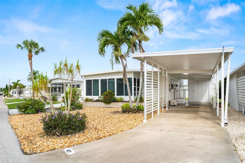 A mobile home with a gravel yard, palm trees, and a covered carport — 822 BOGIE, VENICE, FL