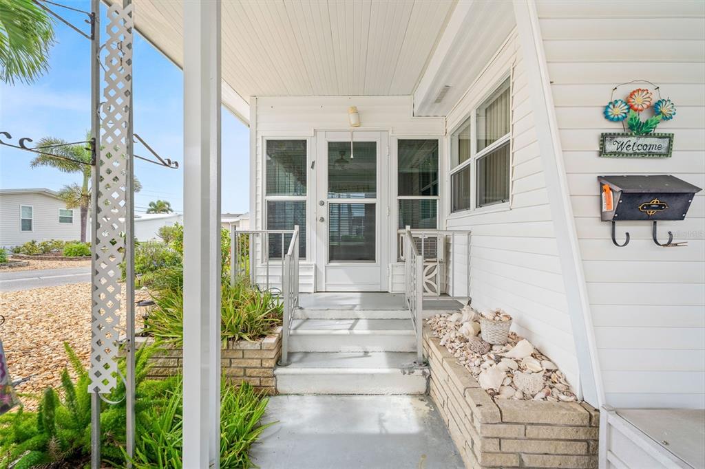 A white exterior entryway features a screened door, concrete steps, and a brick planter — 822 BOGIE, VENICE, FL