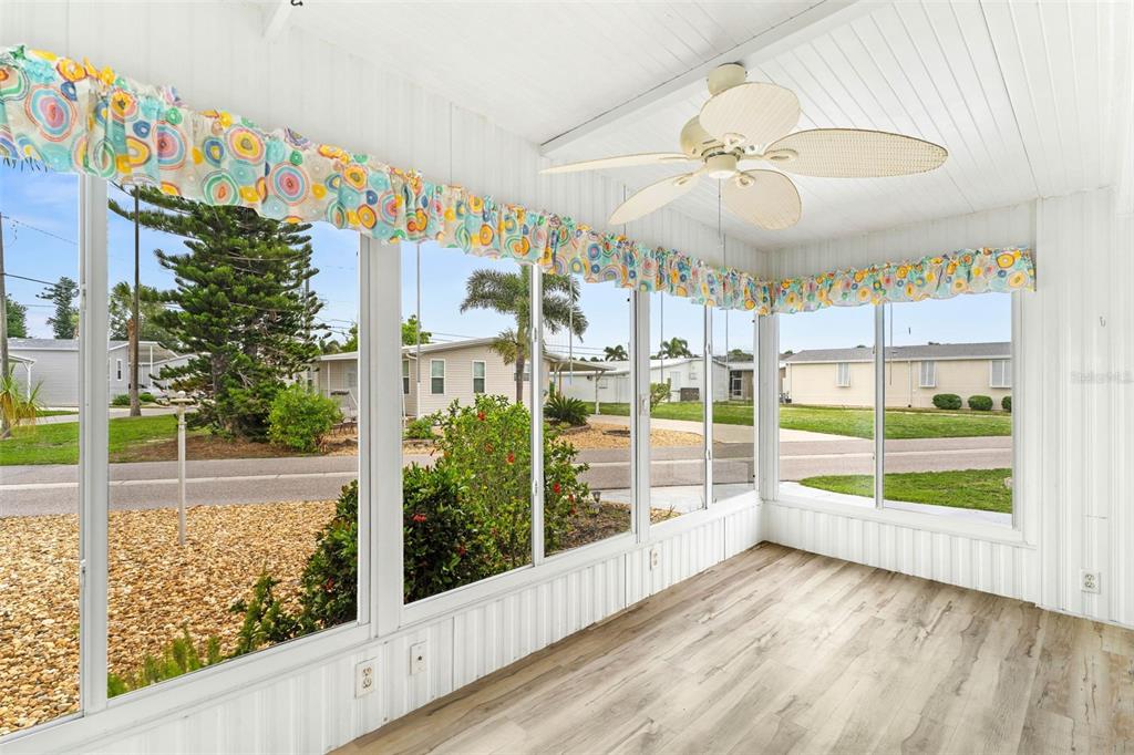 A sunroom features light wood-look flooring, white paneled walls, a ceiling fan, and large windows — 822 BOGIE, VENICE, FL