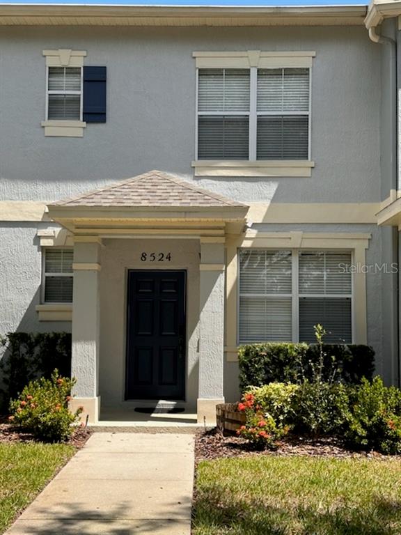 The exterior of a two-story townhouse features a dark front door and beige trim — 8524 DANFORTH DRIVE, WINDERMERE, FL