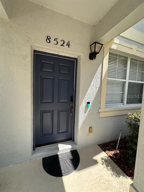 A dark blue front door with a house number above it and a small porch — 8524 DANFORTH DRIVE, WINDERMERE, FL