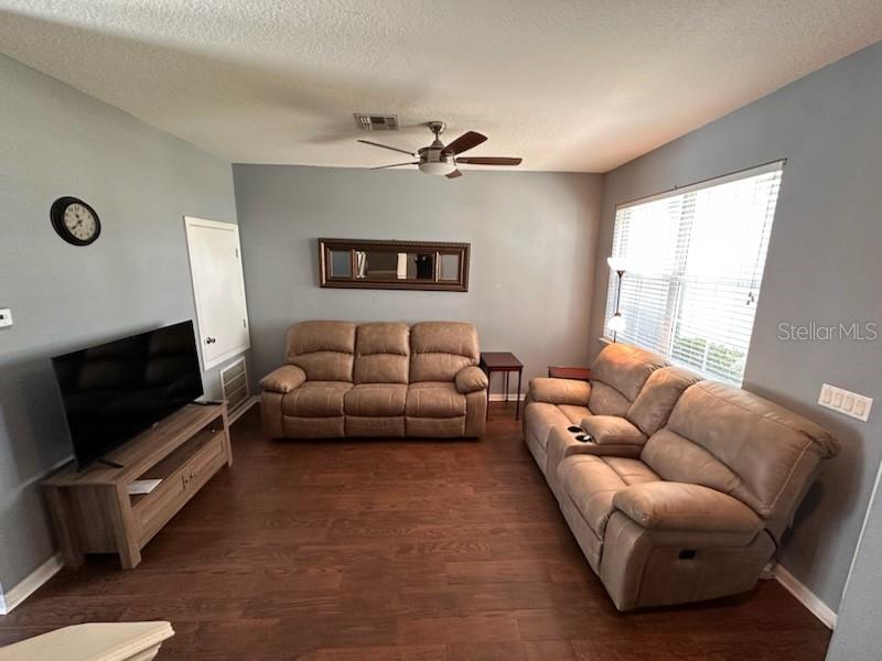 A living room features two brown reclining sofas, a television on a stand, and wood flooring — 8524 DANFORTH DRIVE, WINDERMERE, FL