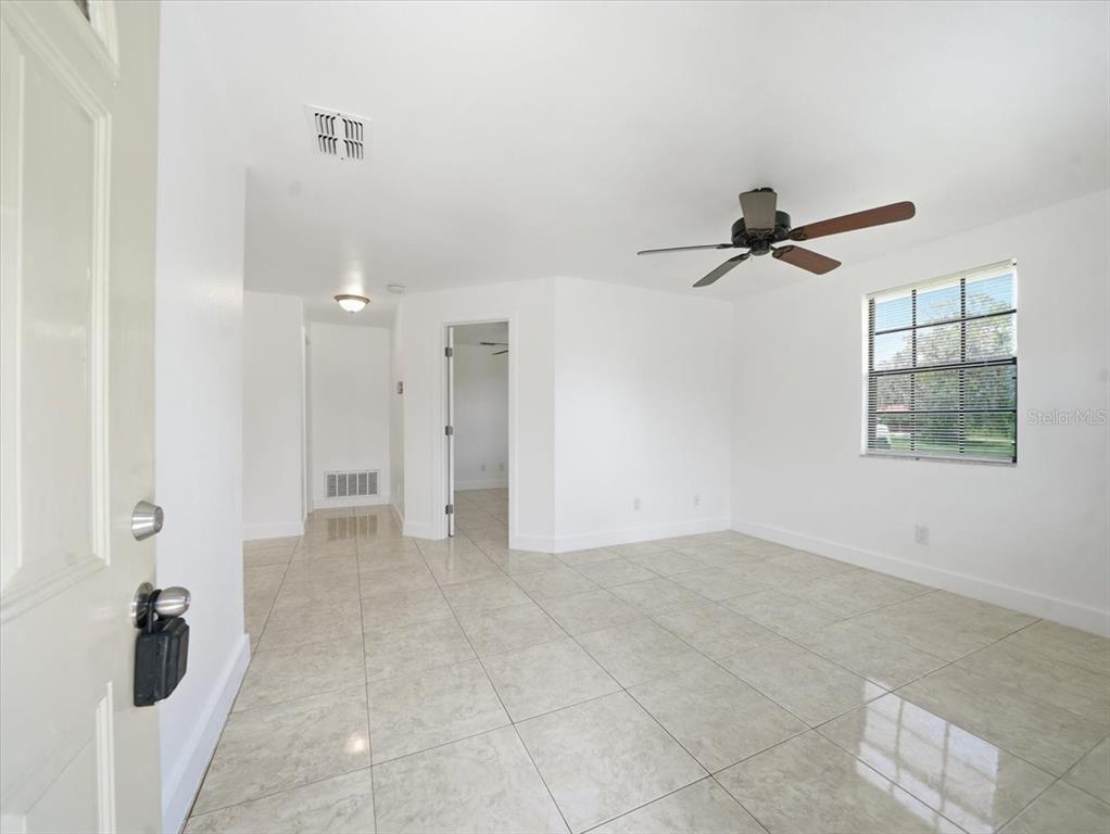 An interior view of a room with white walls, tile flooring, and a ceiling fan — 12823 BUCKEYE DRIVE, HUDSON, FL