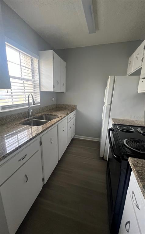 A kitchen features white cabinets, granite countertops, a stainless steel sink, and a black stove — 709 OCEANSIDE CIRCLE UNIT 753, RUSKIN, FL