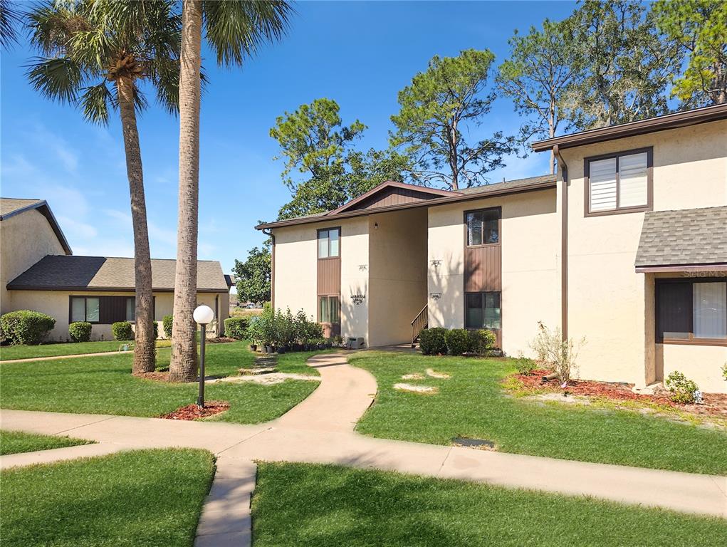 A two-story apartment building with beige stucco walls and a sidewalk leading to the entrance — 623 MIDWAY DRIVE UNIT B, OCALA, FL
