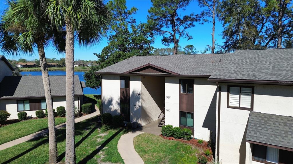 An exterior view of a two-story apartment building with a lake in the background — 623 MIDWAY DRIVE UNIT B, OCALA, FL