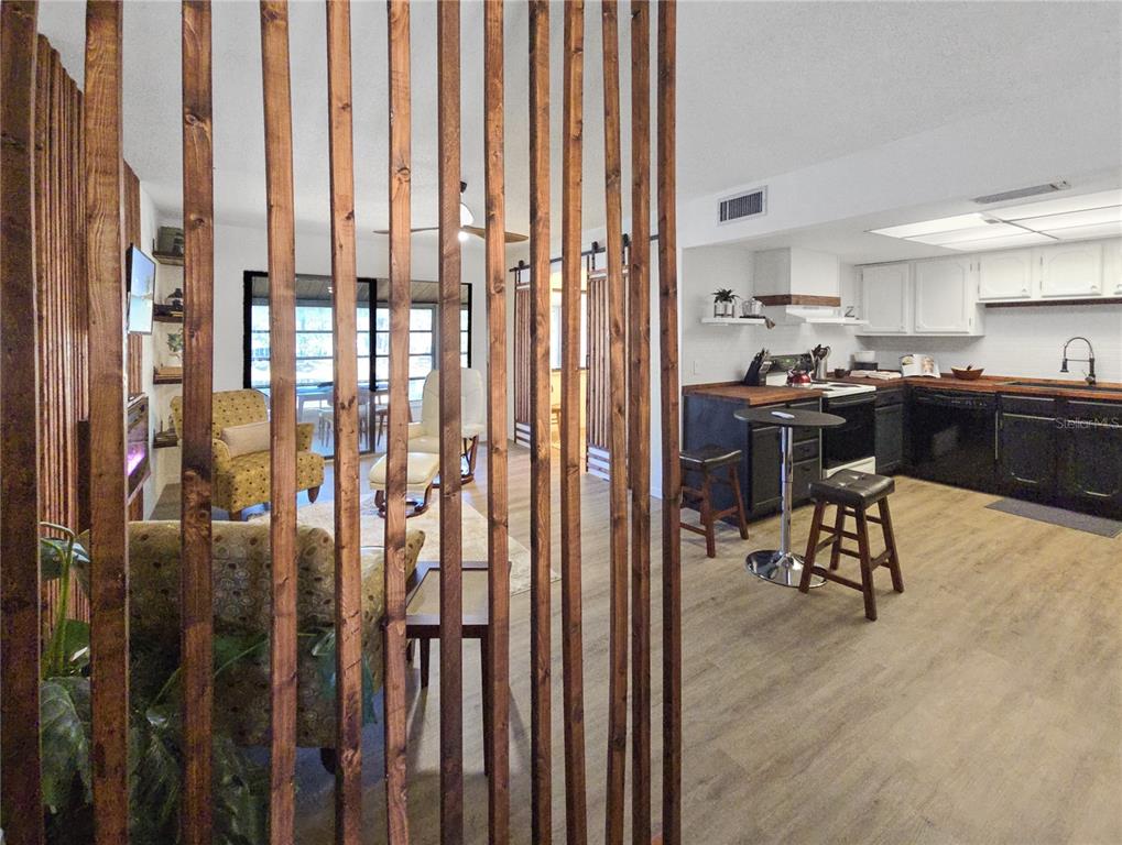 A wooden slat room divider separates a living area from a kitchen with dark cabinets — 623 MIDWAY DRIVE UNIT B, OCALA, FL