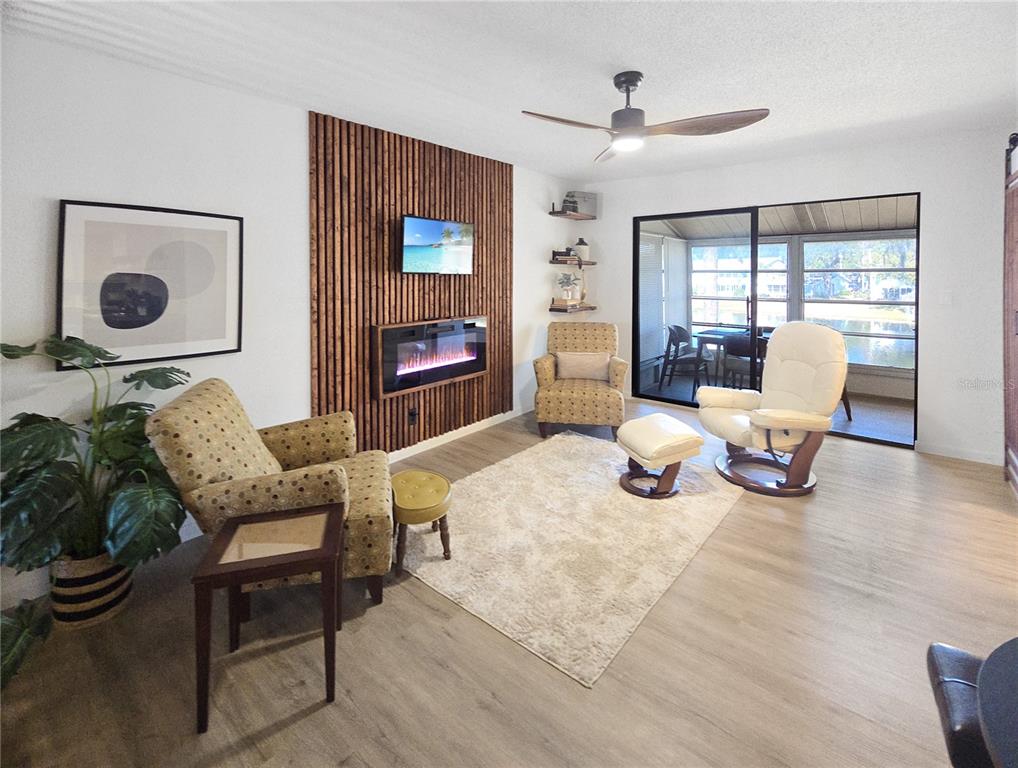 A living room features a wood-slat accent wall with a fireplace, television, and sliding doors — 623 MIDWAY DRIVE UNIT B, OCALA, FL