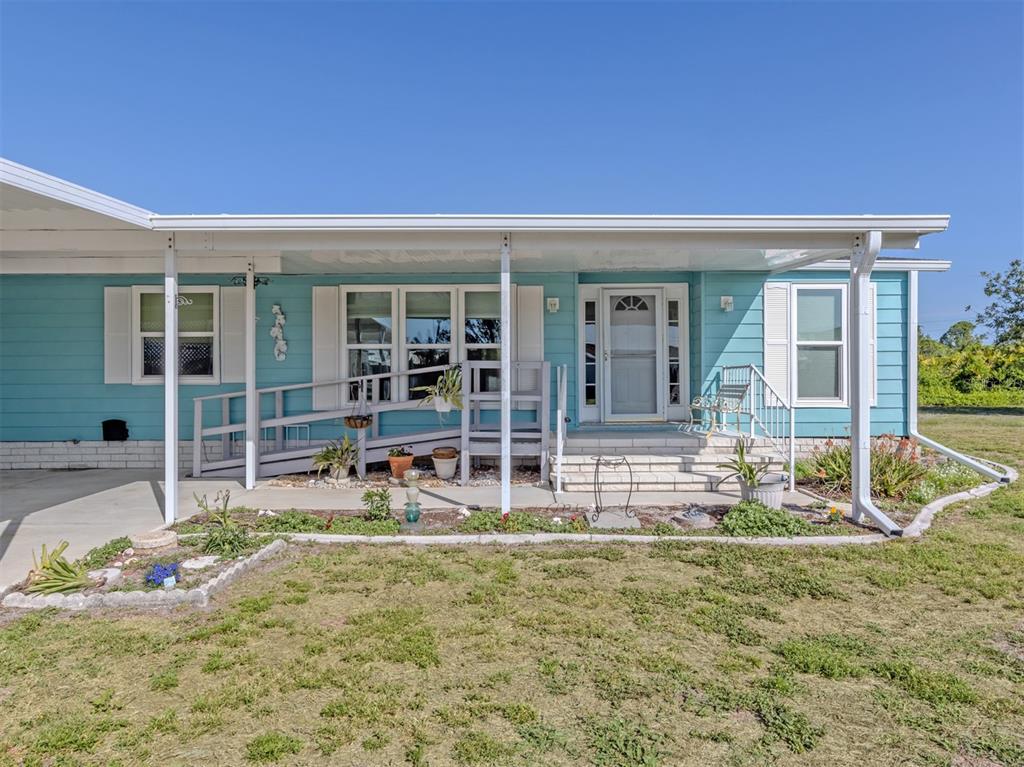 A light blue mobile home with a front porch, wheelchair ramp, and white shutters — 592 PORTSIDE DRIVE, NORTH PORT, FL