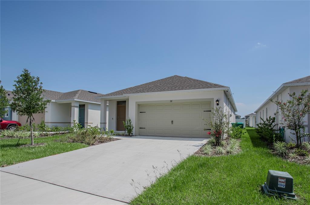 A single-story house with a beige garage, a concrete driveway, and a small front yard — 191 AMBERWOOD WAY, UMATILLA, FL