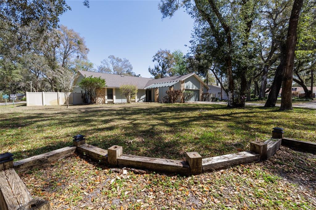 A single-story house with a stone facade and a wooden retaining wall in the foreground — 317 OAK FERN CIRCLE, ORMOND BEACH, FL