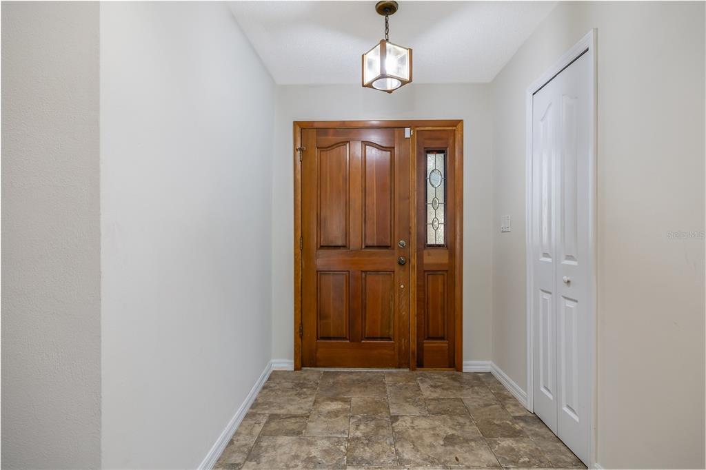 An entryway features a wooden front door with a sidelight, tile flooring, and a pendant light — 317 OAK FERN CIRCLE, ORMOND BEACH, FL