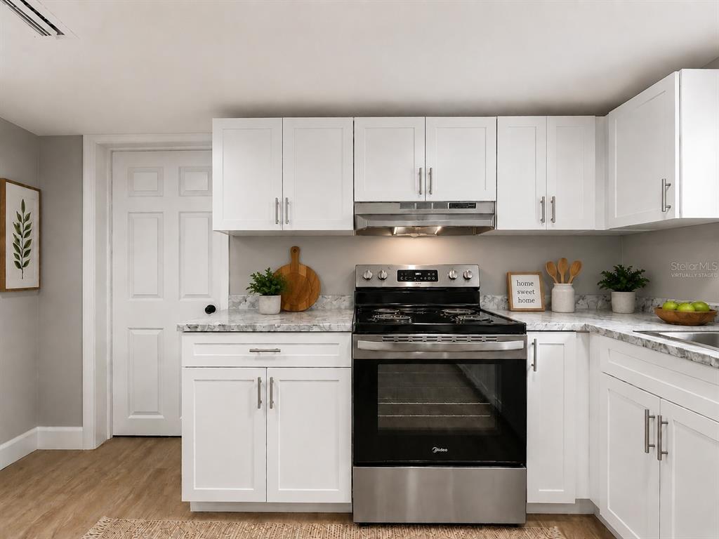 A kitchen features white cabinets, stainless steel appliances, and a marble-patterned countertop — 8117 N KLONDYKE STREET, TAMPA, FL
