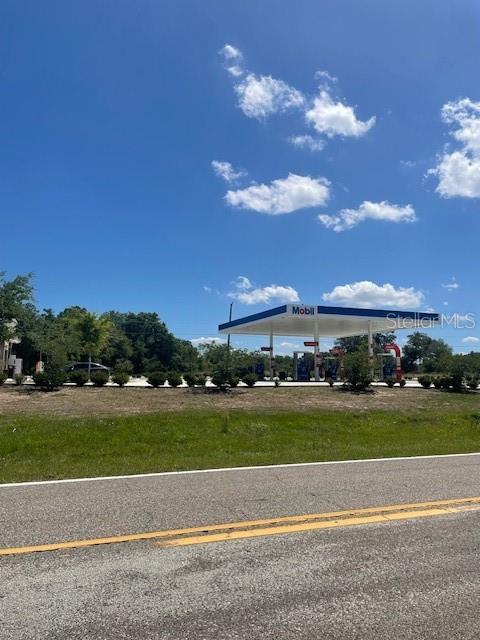 A Mobil gas station stands under a bright blue sky next to a grassy field — 1342 HOMOSASSA DRIVE, POINCIANA, FL