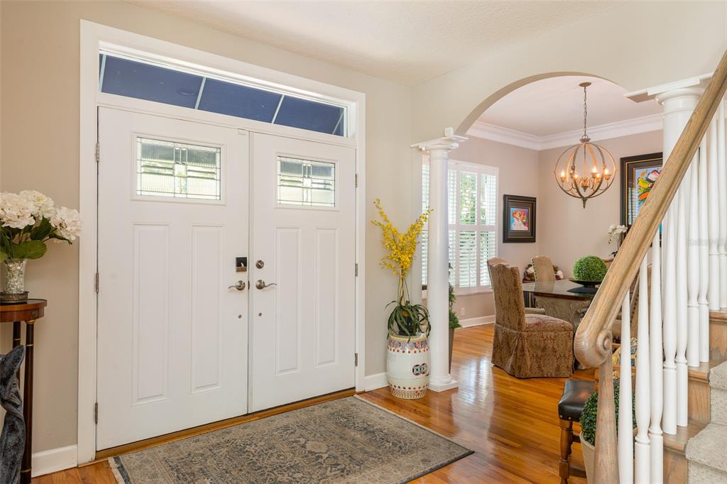 A bright entryway features double white doors, hardwood floors, and an arched opening to a dining — 4721 W SAN MIGUEL STREET, TAMPA, FL