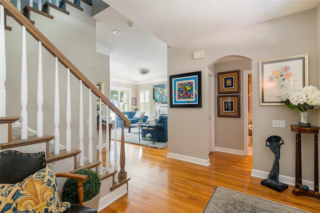 A foyer with hardwood floors, a staircase, and an arched doorway leading to a living room — 4721 W SAN MIGUEL STREET, TAMPA, FL