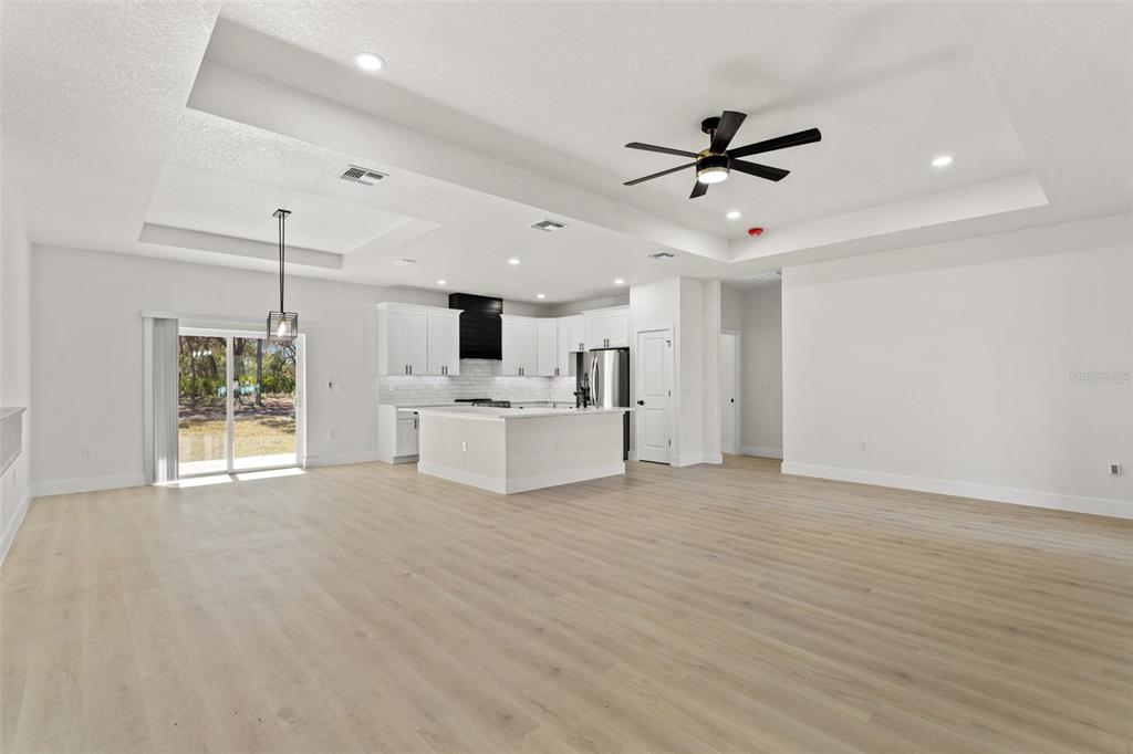 An open-concept kitchen and living area features white cabinetry, a center island, and wood flooring — 10439 GYPSY AVENUE, WEEKI WACHEE, FL