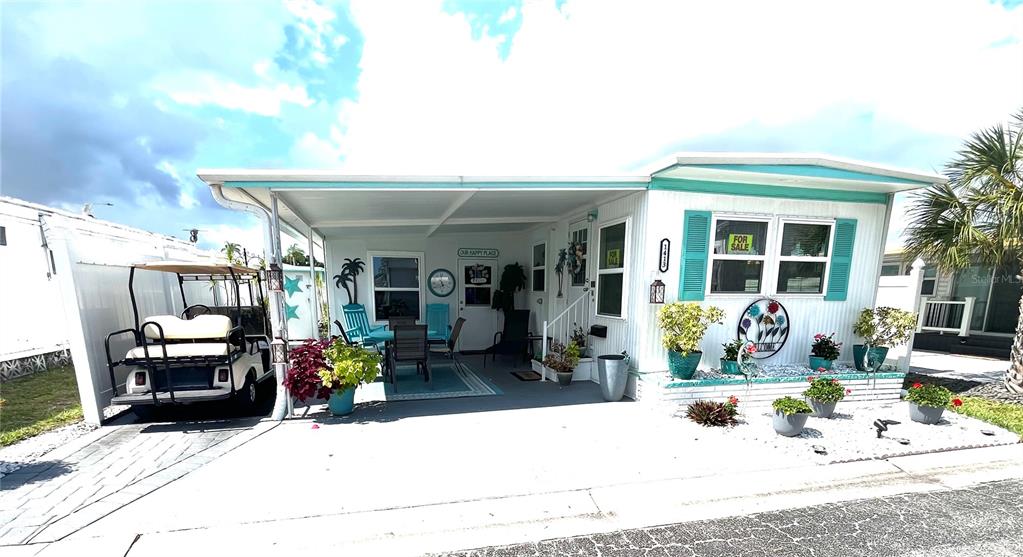The exterior of a mobile home features white siding, teal shutters, and a landscaped rock garden — 1413 24TH AVENUE W, BRADENTON, FL