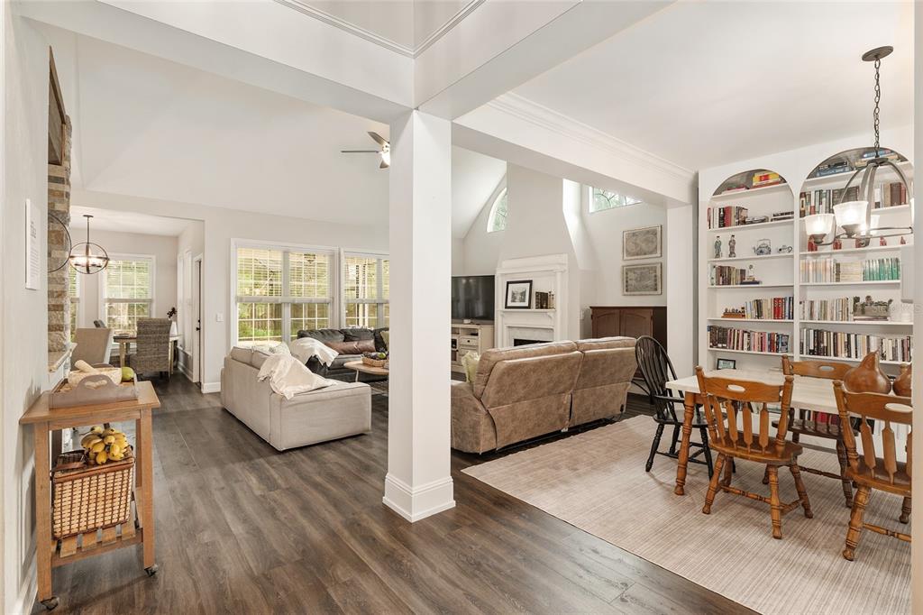 An open-concept living and dining area with wood-look flooring, a fireplace, and built-in bookshelves — 5512 NW 51ST AVENUE, GAINESVILLE, FL