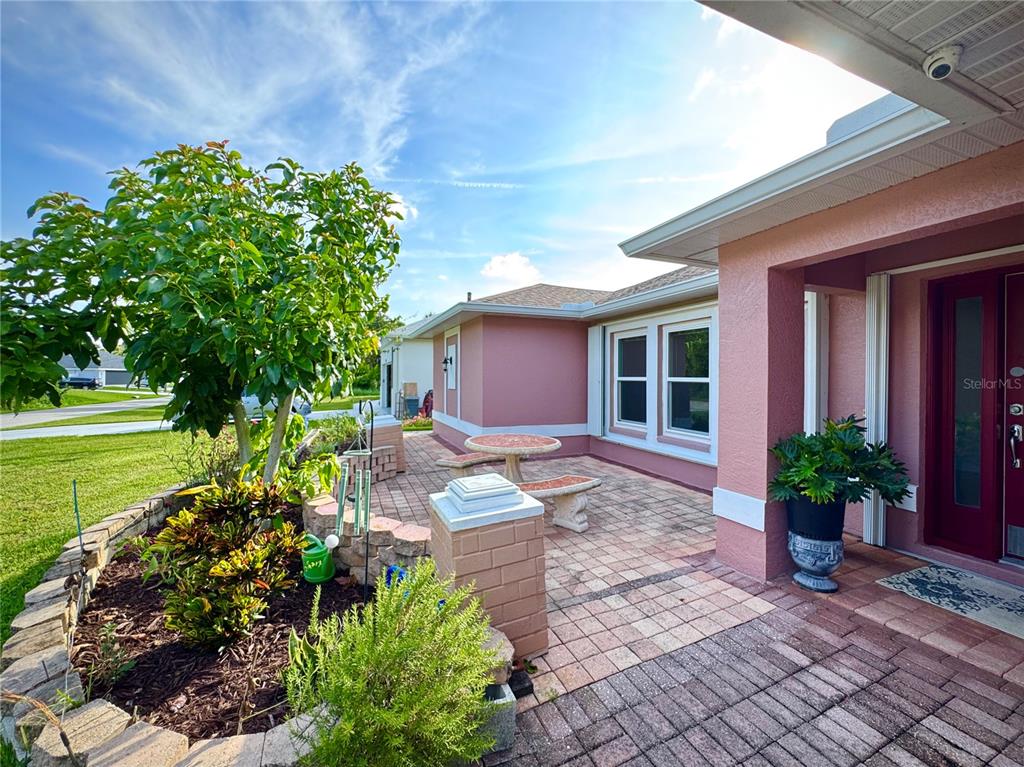 A pink house exterior features a brick patio, a small table, and a landscaped garden — 4353 BOYER TERRACE, NORTH PORT, FL