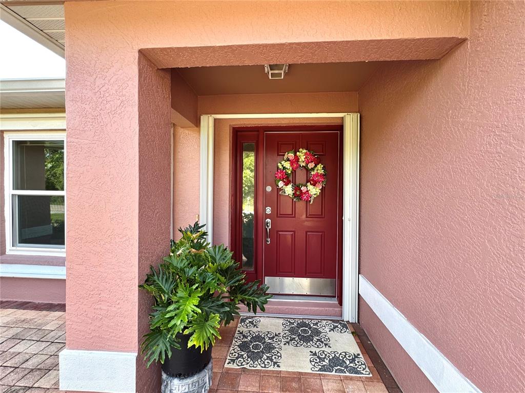 A red front door with a floral wreath sits under a covered entryway — 4353 BOYER TERRACE, NORTH PORT, FL