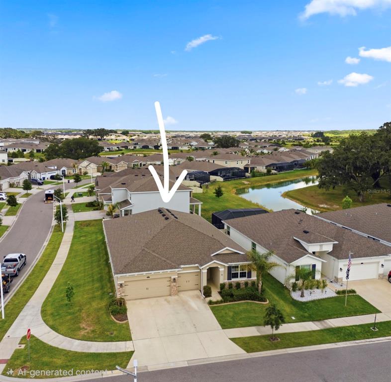 An aerial view shows a suburban house with a two-car garage and a backyard pond — 10403 LAXER CAY LOOP, SAN ANTONIO, FL