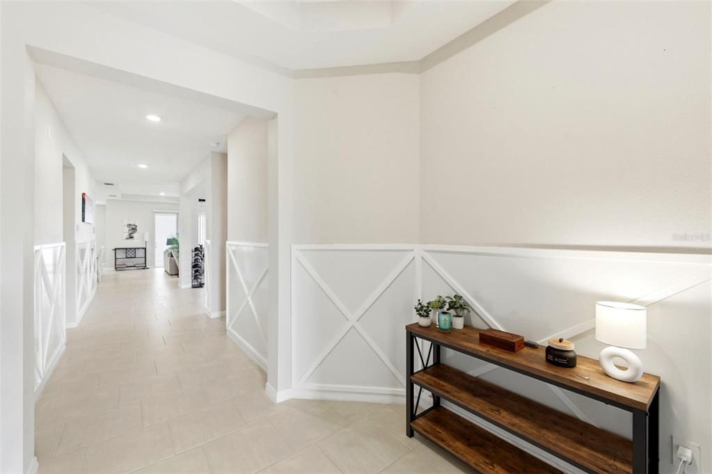 A hallway with white wainscoting and tile flooring leads to an open living space — 10403 LAXER CAY LOOP, SAN ANTONIO, FL