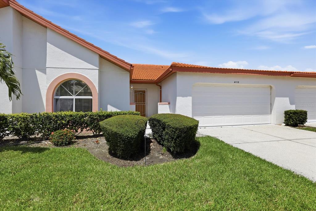 A white stucco house with a tiled roof, a two-car garage, and manicured landscaping — 4112 VALLARTA COURT UNIT 3041, SARASOTA, FL