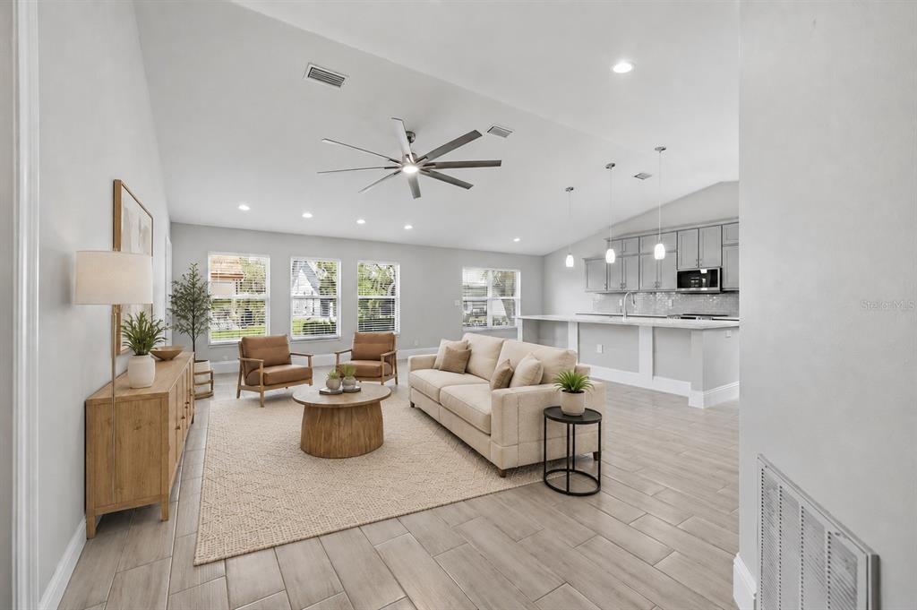 A bright, open-concept living room features a vaulted ceiling, light wood flooring, and a kitchen — 4112 VALLARTA COURT UNIT 3041, SARASOTA, FL