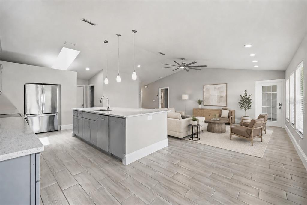 A modern open-concept kitchen and living area with light wood-look tile flooring and gray cabinetry — 4112 VALLARTA COURT UNIT 3041, SARASOTA, FL