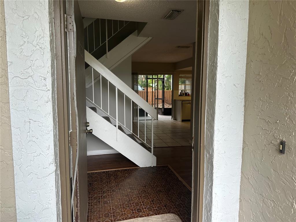 An entryway with a staircase leads into a living area with tile floors and a kitchen — 14752 MORNING DRIVE, LUTZ, FL