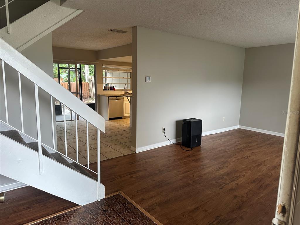 An interior view shows a living area with wood-look flooring, stairs, and an adjacent kitchen — 14752 MORNING DRIVE, LUTZ, FL