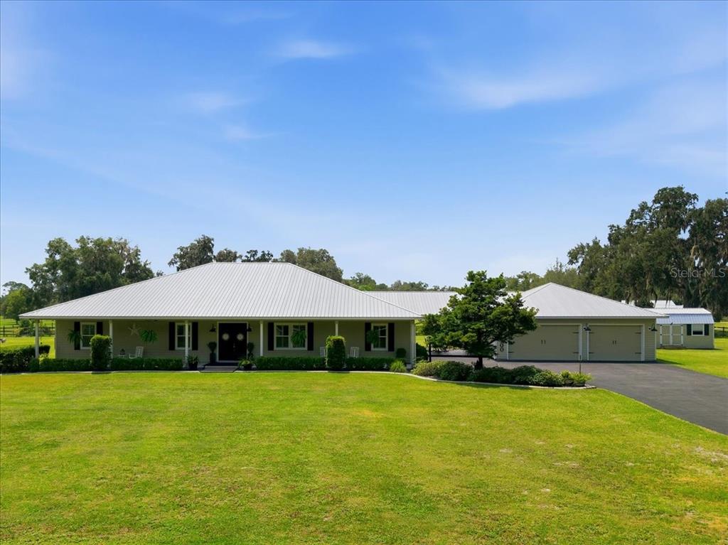 A single-story house with a metal roof and an attached garage sits on a lawn — 1500 SPRING GARDEN RANCH ROAD, DE LEON SPRINGS, FL