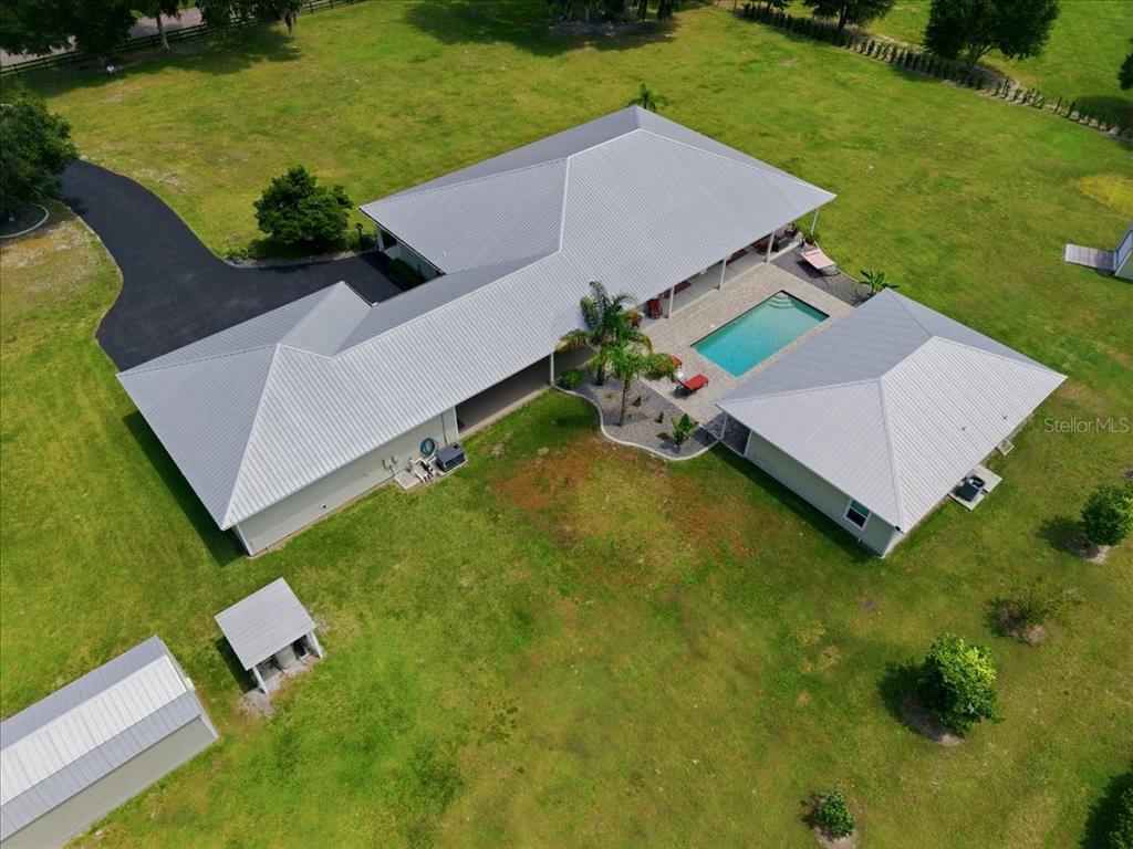 An aerial view shows a house with a metal roof, swimming pool, and detached garage — 1500 SPRING GARDEN RANCH ROAD, DE LEON SPRINGS, FL