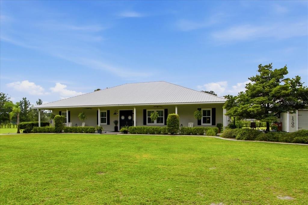 A single-story house with a metal roof and a large front lawn — 1500 SPRING GARDEN RANCH ROAD, DE LEON SPRINGS, FL