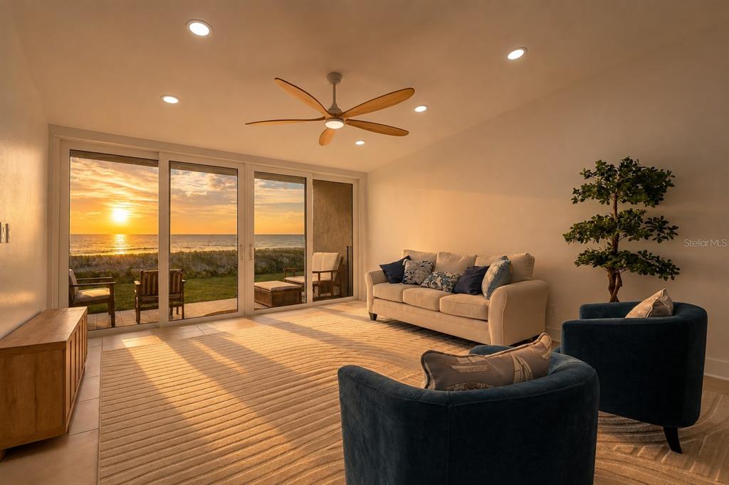 A living room with a beige sofa, two blue armchairs, and sliding doors overlooking the ocean — 2900 GULF BOULEVARD UNIT 108, BELLEAIR BEACH, FL