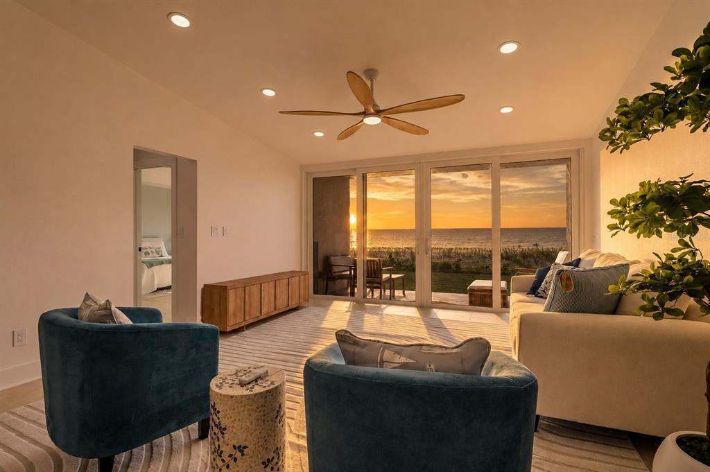 A living room with blue armchairs, a white sofa, and sliding glass doors overlooking the ocean — 2900 GULF BOULEVARD UNIT 108, BELLEAIR BEACH, FL