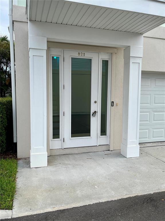 The exterior view shows a white front door with sidelights under a covered entryway — 821 OAK BEND LANE, DUNEDIN, FL