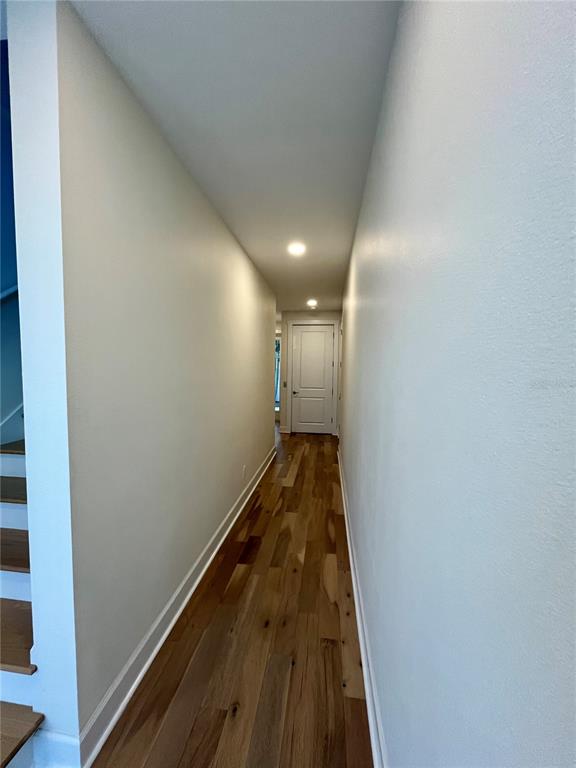 A narrow hallway features light-colored walls, recessed ceiling lights, and wood-look flooring — 821 OAK BEND LANE, DUNEDIN, FL