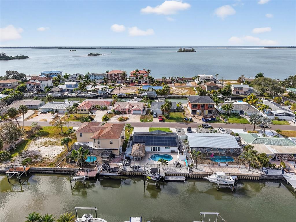 An aerial view of waterfront houses with private docks and swimming pools along a canal — 2171 LAGOON DRIVE, DUNEDIN, FL