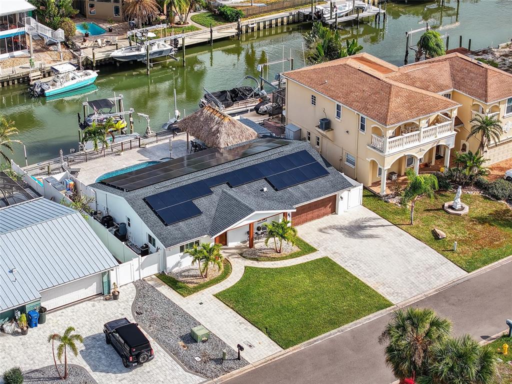 An aerial view of a waterfront house with solar panels, a pool, and a boat dock — 2171 LAGOON DRIVE, DUNEDIN, FL