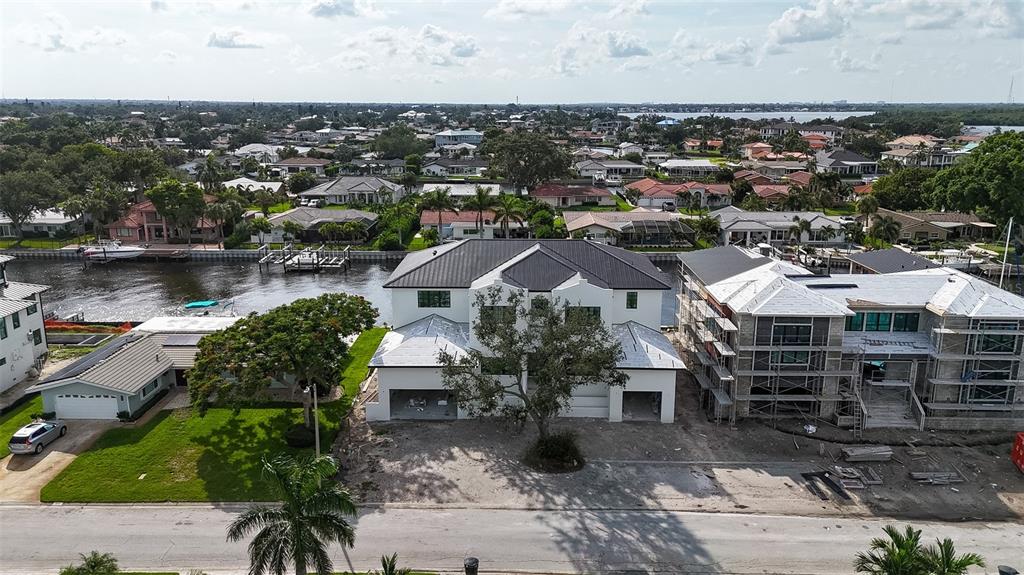 An aerial view shows a modern white house under construction next to a partially built home — 2051 ILLINOIS AVENUE NE, ST PETERSBURG, FL