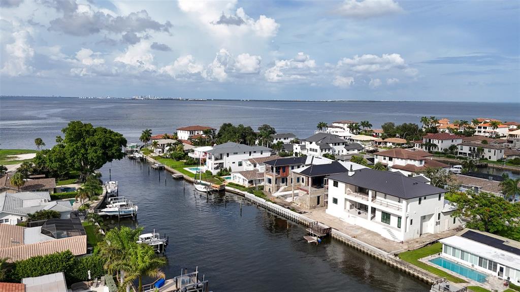 An aerial view shows waterfront homes along a canal leading to a large bay — 2051 ILLINOIS AVENUE NE, ST PETERSBURG, FL