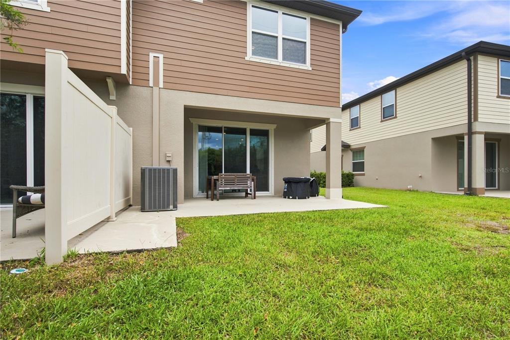 A view of a backyard patio with a privacy fence, sliding glass doors, and HVAC unit — 9237 HILLCROFT DRIVE, RIVERVIEW, FL