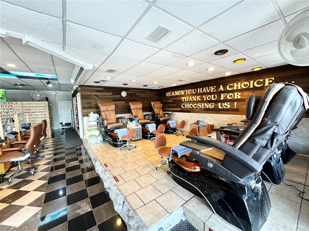 A nail salon features pedicure chairs on a raised platform with wood-paneled walls and tile flooring — 3080 BEE RIDGE ROAD, SARASOTA, FL
