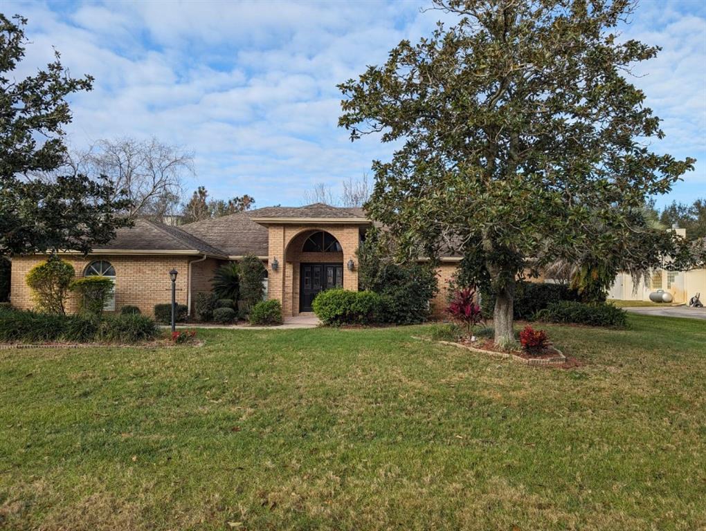 A single-story brick house with a prominent arched entryway and a large front yard — 72 SPRING LAKE DRIVE, DEBARY, FL