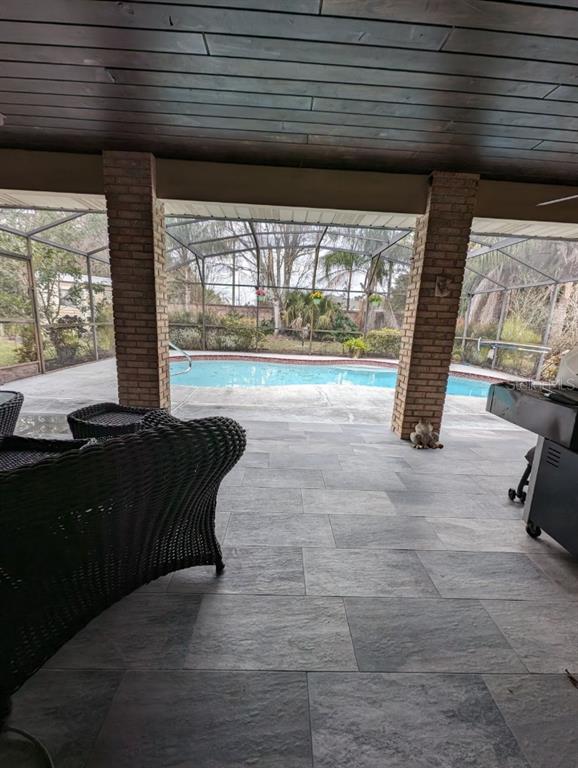 A covered patio with large gray floor tiles overlooks a swimming pool enclosed by screens — 72 SPRING LAKE DRIVE, DEBARY, FL