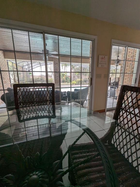 A dining area with a glass table and wicker chairs overlooks a screened-in pool patio — 72 SPRING LAKE DRIVE, DEBARY, FL